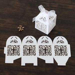 Detail of white laser-cut wedding candy box with cross pattern and silk ribbon bow