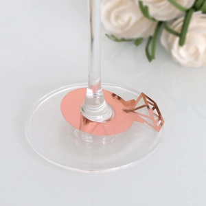 Detalle de tarjetas de mesa con forma de anillo de oro rosa en copa de vino