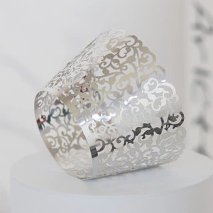 Macro shot of silver laser-cut cupcake wrappers with elegant vine and leaf filigree details