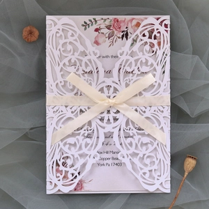 Detailed laser-cut white butterfly wedding invitation with floral insert and beige ribbon