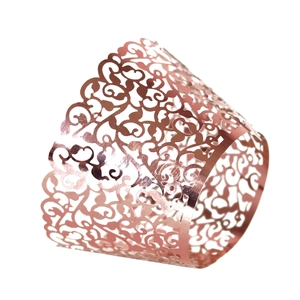 Macro shot of rose gold laser cut cupcake wrapper with intricate floral scroll patterns