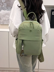 Minimalist avocado green nylon backpack for women featuring a circular logo and cute charm