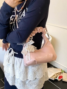 Light pink pleated handbag with pearl charm and white lace bow shown from top view