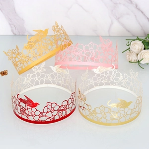 Laser-cut crown cake wrappers with floral and bird patterns in gold and pink finishes