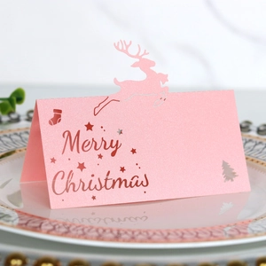 Detail der rosa Glitzer-Weihnachtsplatzkarte mit Rentier-Ausschnitt auf einem Teller