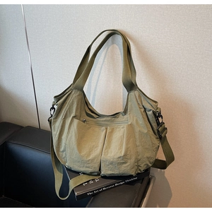 Detail of olive green nylon tote bag featuring front pockets and adjustable strap