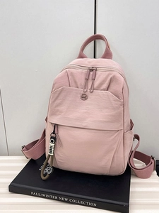 Minimalist pink nylon backpack for women featuring stylish metal logo and hanging charm