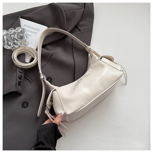 Détail du sac porté épaule beige en simili cuir avec pompons sur un blazer