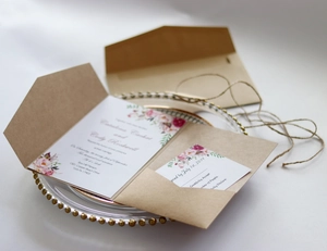 Rustic kraft wedding invitation set with floral motifs and RSVP card on a gold glass tray