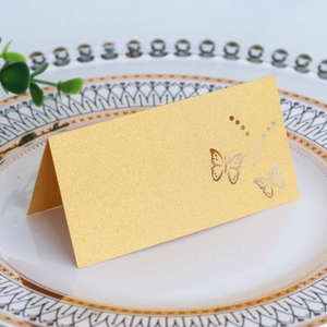 Detailed view of a gold laser-cut butterfly place card on a white dinner plate