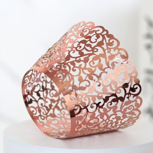 Macro detail of rose gold laser cut cupcake wrapper with intricate vine pattern