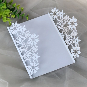 Detailed laser-cut snowflake pattern on white pearlescent paper invitation cover