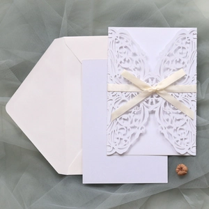 Detailed laser-cut wedding invitation featuring hollow patterns and ivory ribbon bow