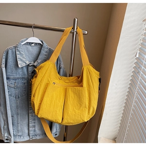 Detail view of a bright yellow large capacity tote bag featuring multiple pockets and straps