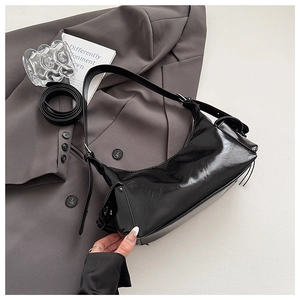 Vue latérale détaillée d'un sac sous les bras noir brillant sur un costume gris chic