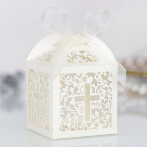 Macro shot of white laser-cut favor box with hollow cross design and organza ribbon