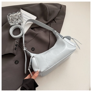 Détail du sac à bandoulière en cuir bleu clair avec sangle réglable sur un blazer gris