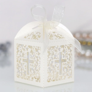 Macro shot of laser-cut white favor box with elegant cross cutout and organza ribbon