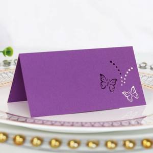 Purple laser-cut butterfly place card on white ceramic plate for wedding tables