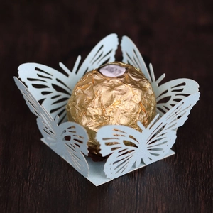 Detailed laser-cut blue butterfly favor holder with a gold-wrapped chocolate sphere