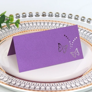 Close-up of purple laser-cut butterfly place card on white porcelain plate for weddings