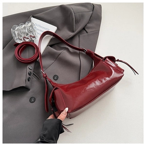 Détail du sac bandoulière en cuir verni bordeaux avec finition brillante et bandoulière réglable