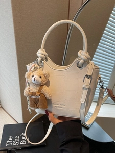 White faux crocodile skin bucket bag with teddy bear pendant and adjustable strap