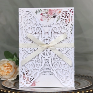 Detailed laser-cut white wedding invitation card featuring butterfly pattern and ribbon bow