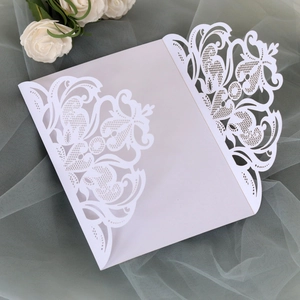 Macro detail of laser-cut floral hollow pattern on ivory white wedding invitation