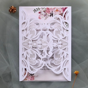 Detail of laser-cut lace wedding invitation with floral insert and elegant stationery