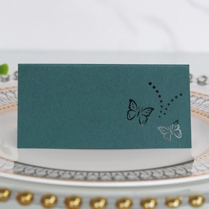 Detail of dark green laser-cut butterfly place card on an elegant dinner plate