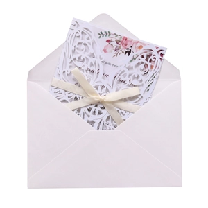 Laser cut white wedding invitation featuring delicate floral patterns and cream ribbon