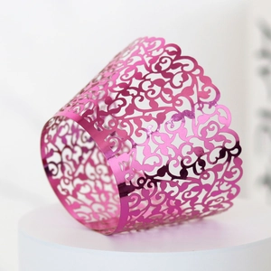 Macro shot of laser-cut pink metallic vine pattern on a cupcake wrapper decoration
