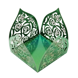 Macro detail of laser-cut rose hollow patterns on metallic emerald green gift boxes