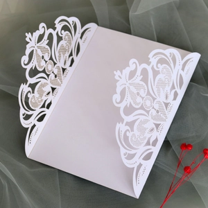 Detail of white laser-cut wedding invitation with intricate lace floral patterns