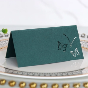 Macro shot of dark green laser-cut butterfly table card on elegant white porcelain plate
