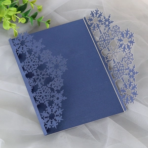 Detail of laser-cut snowflake edges on navy blue pearlescent paper invitation sleeve