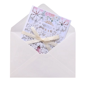 Macro shot of laser-cut snowflake invitation with ribbon bow and matching envelope