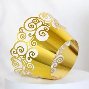 Close-up of golden laser-cut cupcake wrappers with elegant hollow scroll patterns