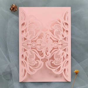 Close-up of pink laser-cut lace wedding invitation cover with intricate floral patterns