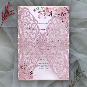 Pink glitter laser-cut wedding invitation with floral insert and intricate hollow design