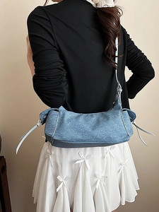Sac bandoulière en denim bleu avec liseré blanc et cordons porté par une femme mannequin