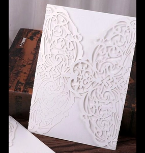Detail of white laser-cut wedding invitation featuring elegant scrollwork and floral patterns