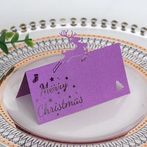 Details der lila Glitzer-Rentier-Weihnachtskarte mit Laser-Cut-Schriftzug auf Teller