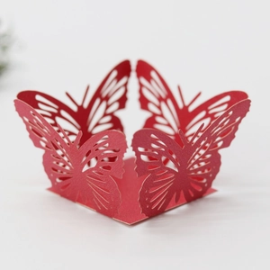 Macro view of laser-cut red butterfly pattern on paper cupcake liner for weddings