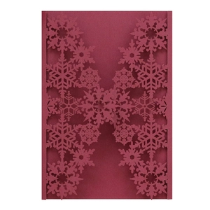 Macro detail of laser-cut snowflake patterns on dark red pearlescent cardstock invitation