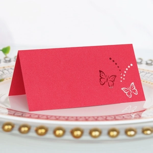 Detail of red hollow butterfly laser-cut place card on a white decorative dinner plate