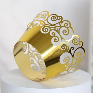 Close-up of laser-cut gold mirror paper cupcake wrappers with elegant cloud patterns