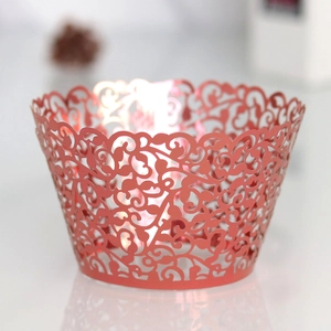 Macro detail of red laser-cut cupcake wrappers with elegant floral vine hollow patterns