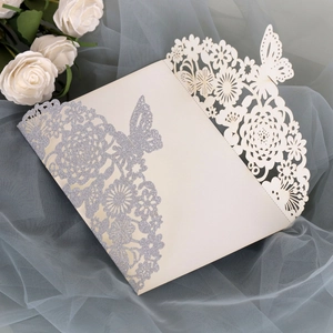 Detail of laser-cut cream invitation with silver glitter floral and butterfly patterns